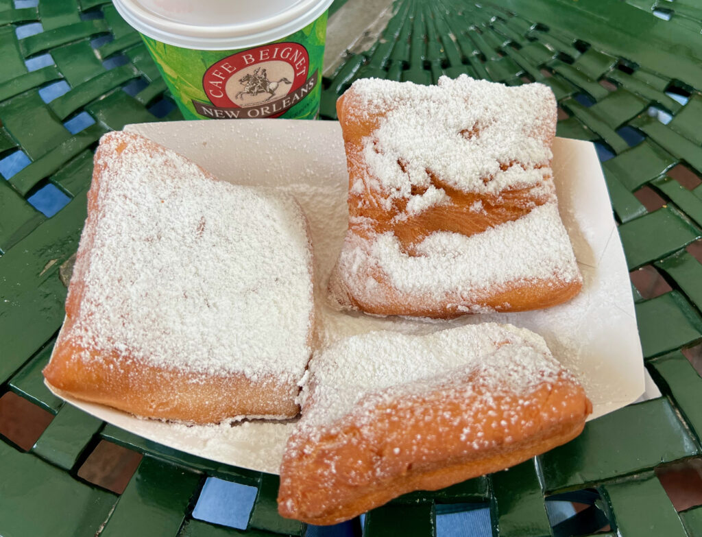 Three beignets and a to-go cup of coffee