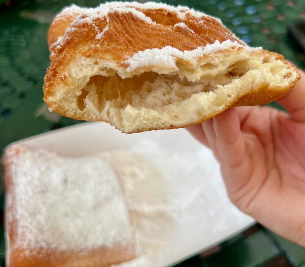 A half-eaten beignet with the dough on the inside showing