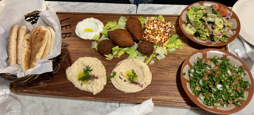 A platter of assorted Lebanese appetizers, including bread, hummus, cheese, and salads.
