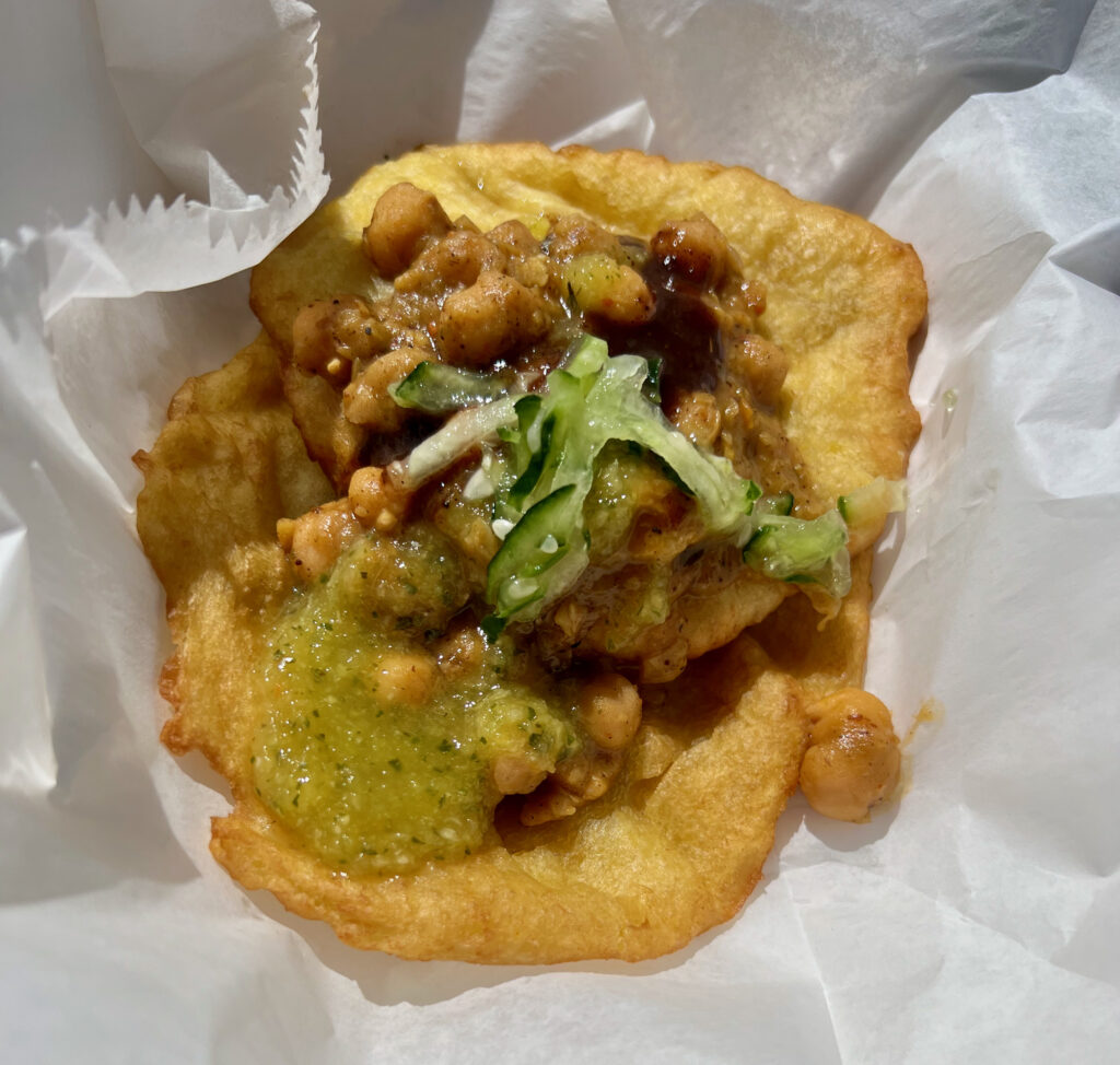 Two doubles, a famous vegan Trinidadian street food made of curry chickpeas between 2 turmeric flatbread with chutney. 