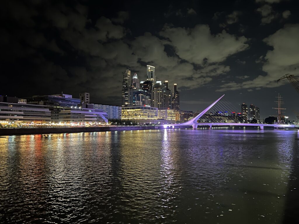 A large river with numerous skyscrapers and an illuminated bridge