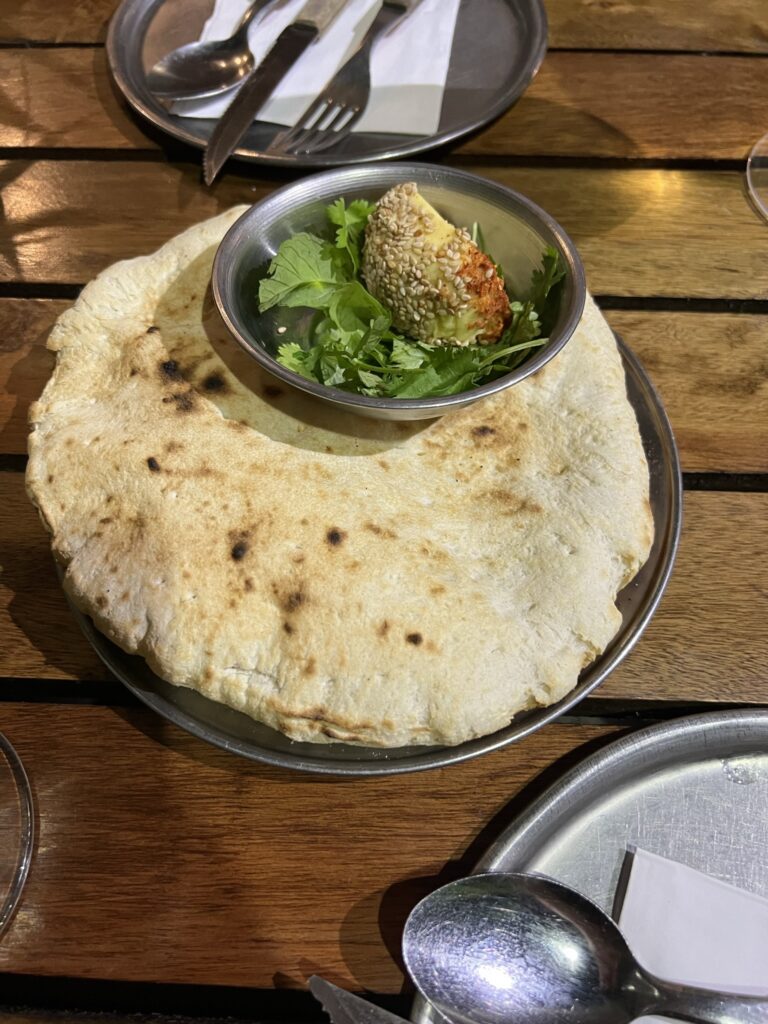 Puffy naan topped with garnishing and a curry sauce