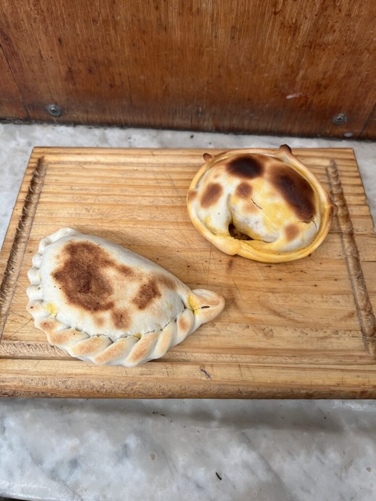 Two empanadas on a wooden board