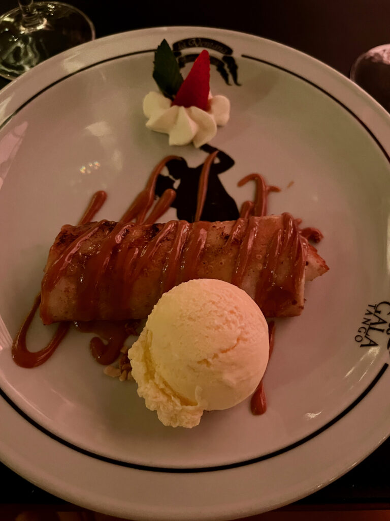 A crepe dessert covered in dulce de leche sauce and paired with a scoop of vanilla ice cream.