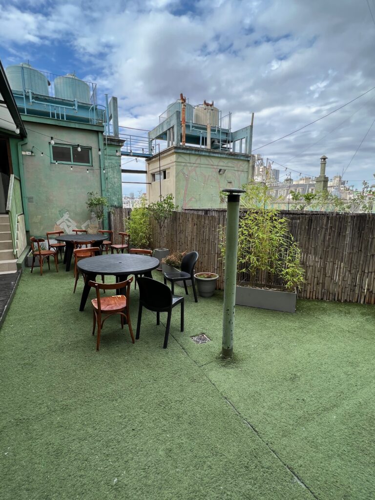 A rooftop common area with outdoor seating and fake grass on the floor.